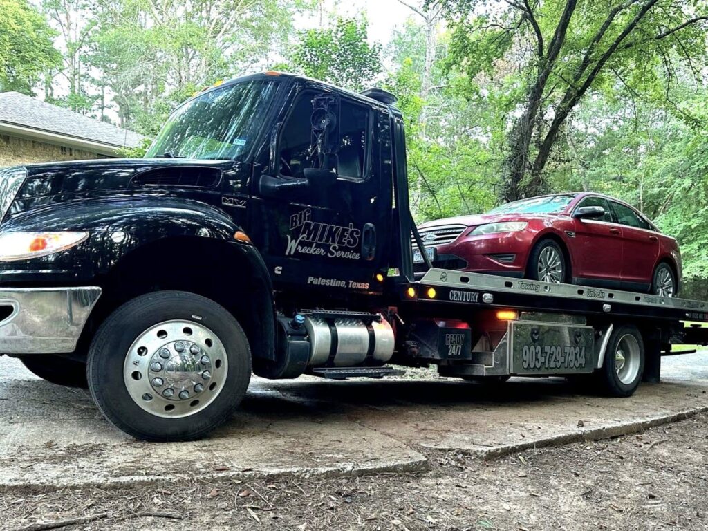 Big Mike’s Wrecker Service flatbed tow truck hauling a red sedan in Palestine TX