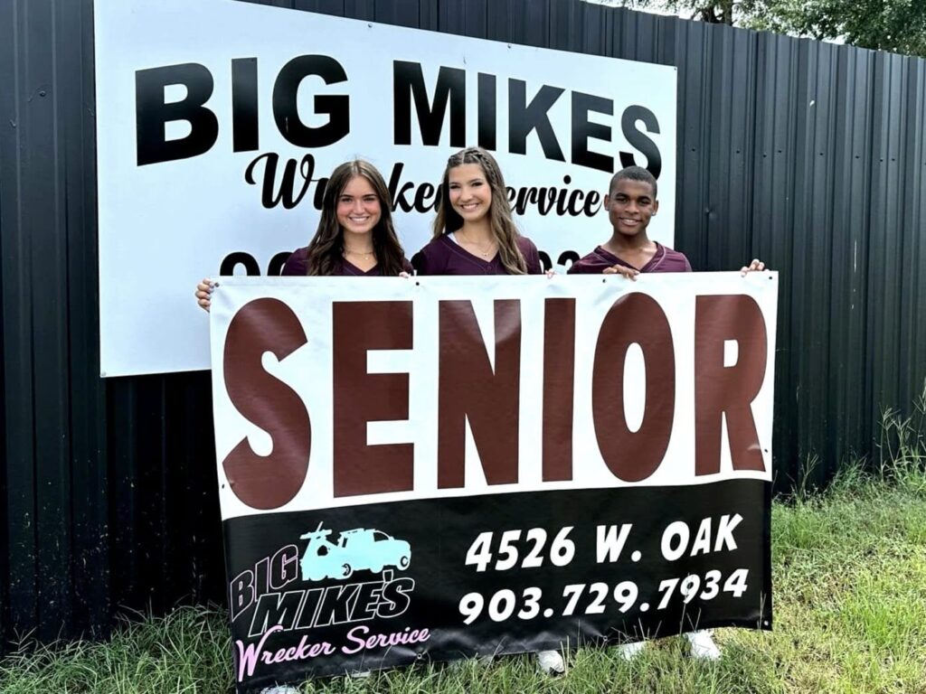 High school seniors posing with Big Mike’s Wrecker Service banner in Palestine Texas