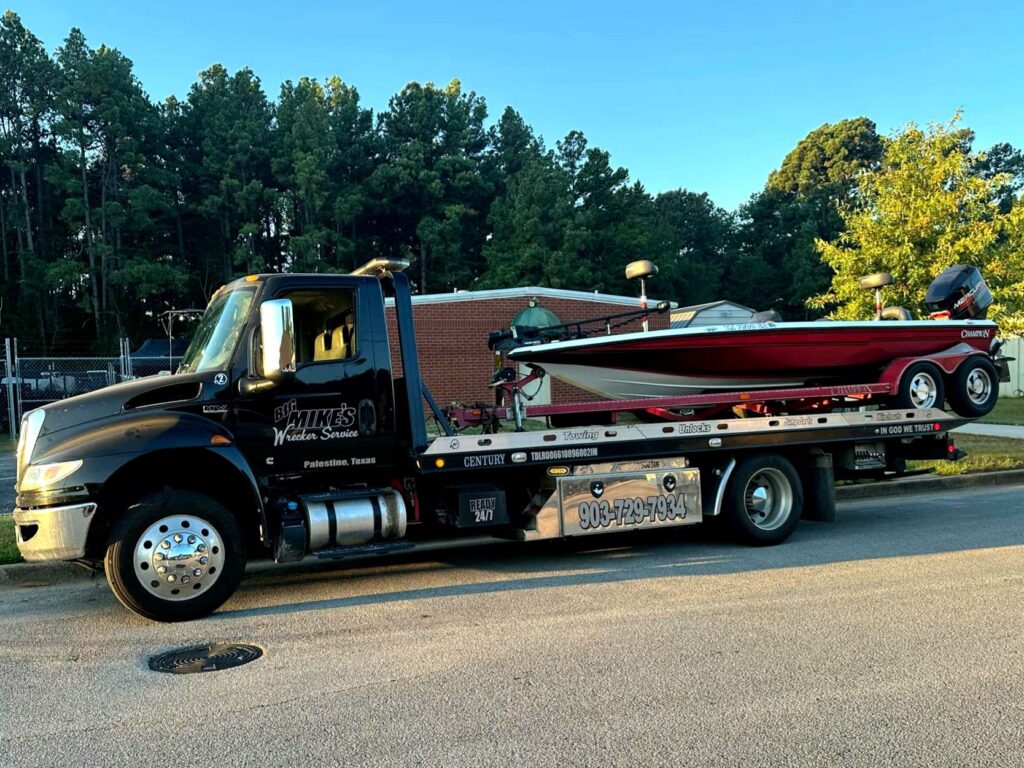 Flatbed tow truck from Big Mike’s Wrecker Service hauling bass boat in Palestine TX
