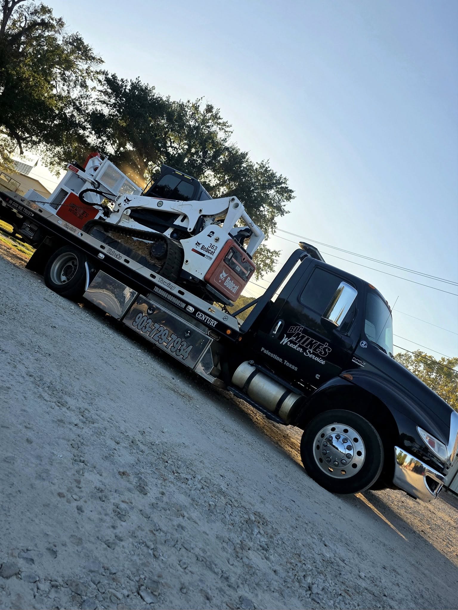 Big Mike’s Wrecker Service transporting Bobcat skid steer loader on flatbed tow truck in Palestine Texas