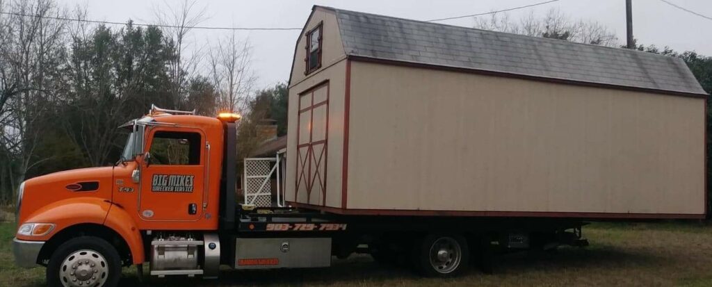 Big Mike’s Wrecker Service flatbed tow truck transporting a storage shed in Palestine TX